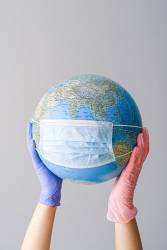 hands-with-latex-gloves-holding-a-globe-with-a-face-mask-4167544